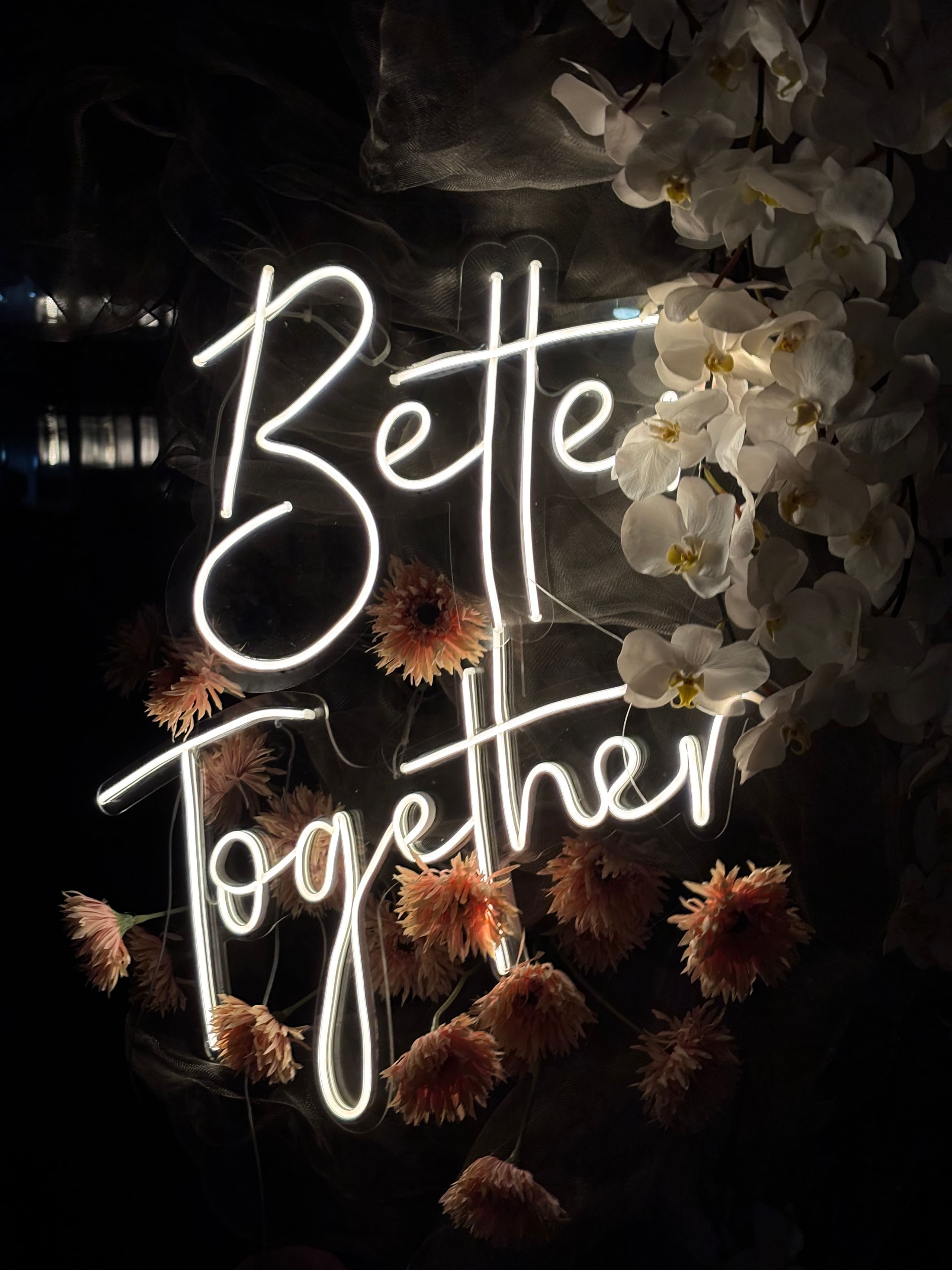 A fragment of neon script among dried blooms