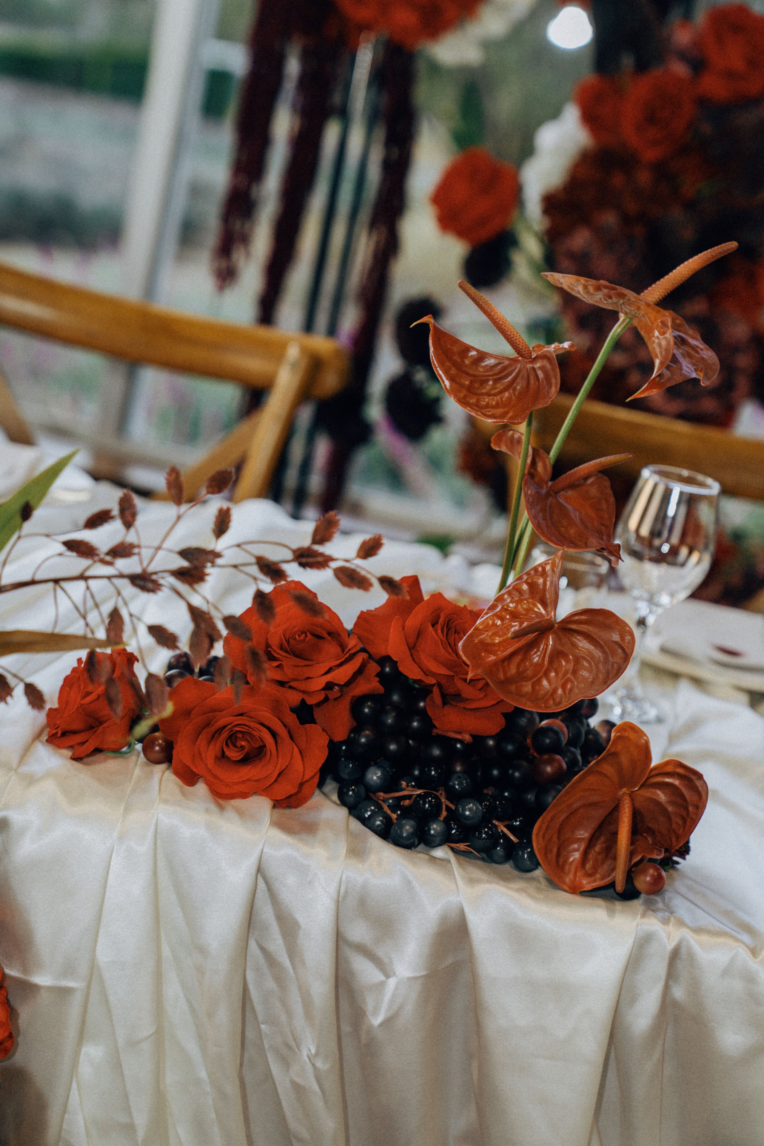 Red roses, anthurium and dark grapes on ivory satin